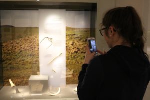 Teenage girl taking a photo of a display at Wiltshire Museum.