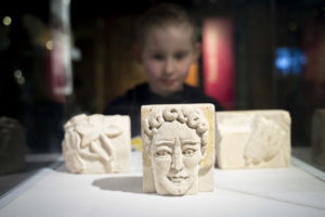 Three carved stone pieces with child behind looking at them