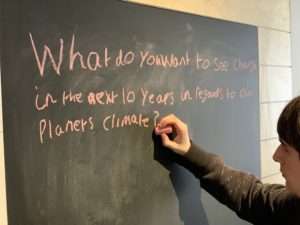 Young man writing climate change message on blackboard