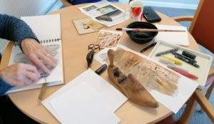 Arts materials on a table and woman sketching