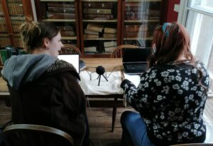 two women sitting at a table discussing the podcast