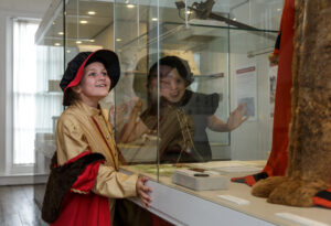 Two young girls wearing a period costume looking at a display of an authentic period costume