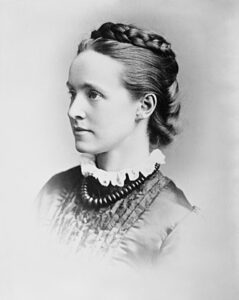 Black and white image of Millicent Fawcett wearing a dress with plaited hair