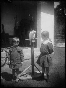 An image showing the cut and style of coats worn by boys at the time (boy Peter on the left). Peter and Jean Lindsay, ca. 1900-1912, by Lionel Lindsay, Flickr's for Wikimedia Commons.