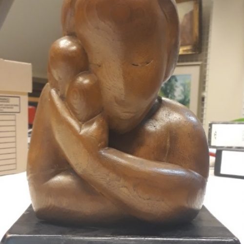 Wooden sculpture of a child holding a dove.